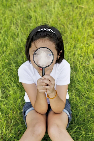 Asiatique petite fille tenant une loupe en plein air — Photo