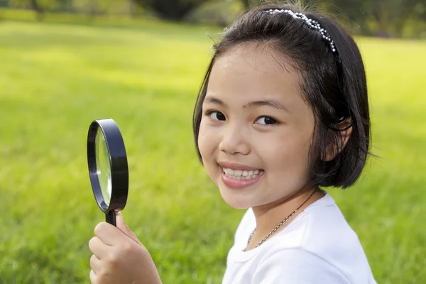 Gadis kecil Asia memegang kaca pembesar di luar ruangan — Stok Foto