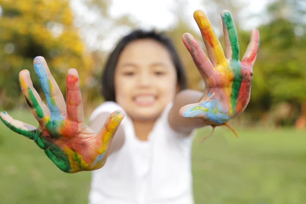 Asiatisches kleines Mädchen mit in bunten Farben bemalten Händen — Stockfoto