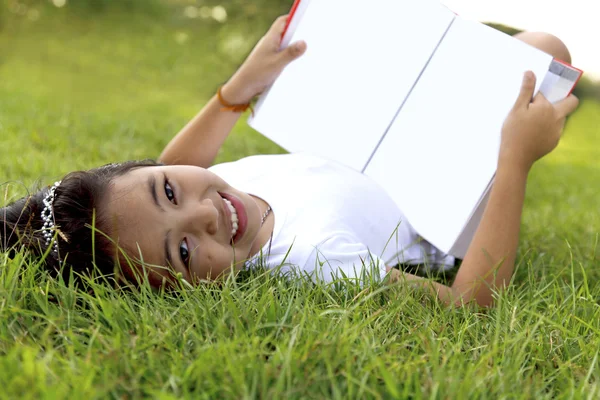 Asiatique petite fille se détendre et lire un livre dans le parc — Photo