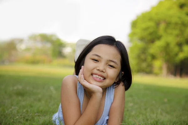 Asiática niña relajarse y sonreír felizmente en el parque —  Fotos de Stock