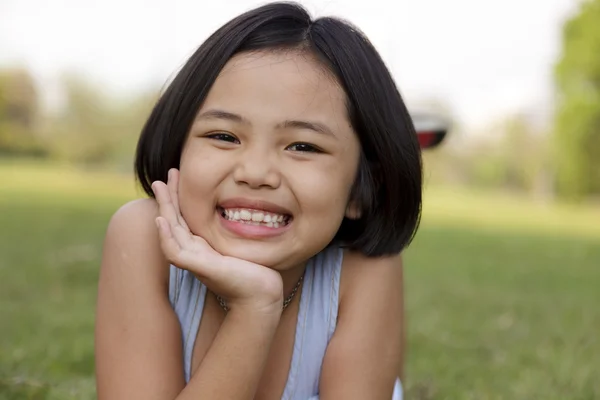 Asyalı küçük kız sakin ve mutlu bir şekilde gülümseyerek parkta — Stok fotoğraf
