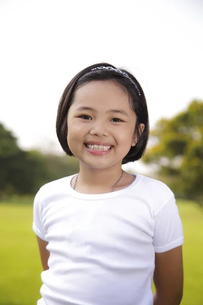 Asiática chica relajarse y sonriendo felizmente en el parque — Foto de Stock