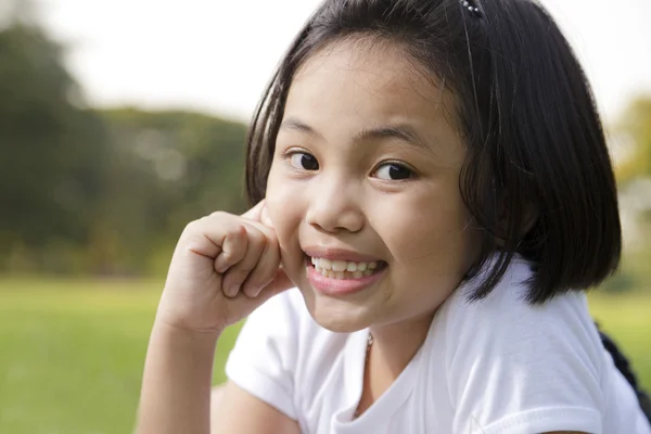 Asiatisches kleines Mädchen entspannt sich und lächelt glücklich im Park — Stockfoto