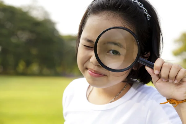 Asiatiska liten flicka håller ett förstoringsglas i utomhus — Stockfoto