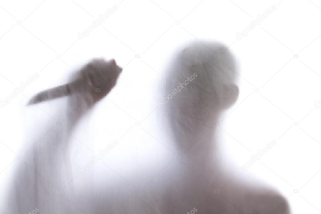 Man standing behind frosted glass and holding a knife