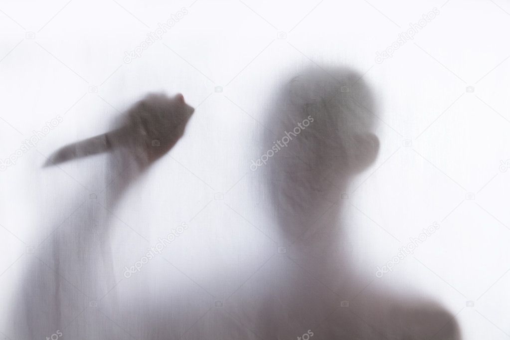 Shadow of men standing behind thin fabric and holding a knife