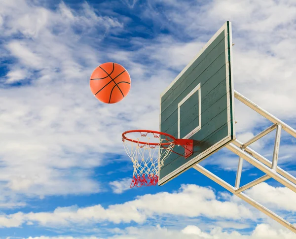 Cesta de baloncesto y pelota en el cielo azul — Foto de Stock