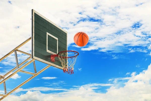 Cesta de baloncesto y pelota en el cielo azul — Foto de Stock