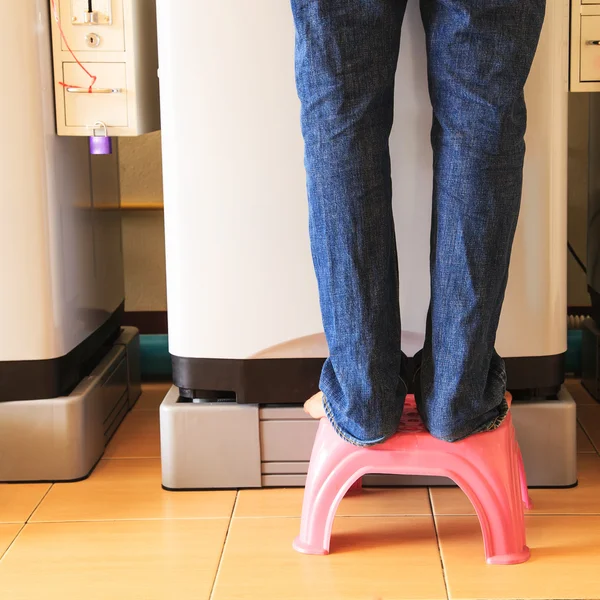 Uomo in piedi davanti alle lavatrici moneta — Foto Stock