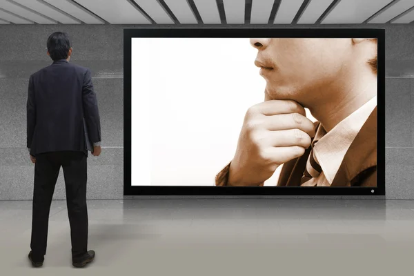 Businessman standing looking at the TV screen — Stock Photo, Image