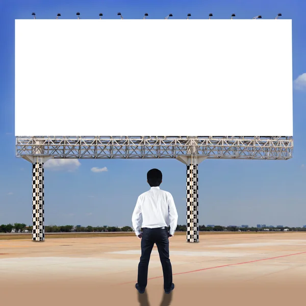 Бизнесмен стоит и смотрит на чистый рекламный щит — стоковое фото
