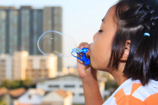 Menina está soprando bolhas — Fotografia de Stock