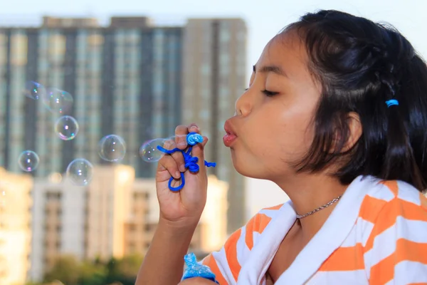 Menina está soprando bolhas — Fotografia de Stock