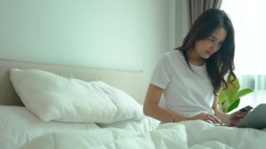 Yatakta online alışveriş yapmak için dizüstü bilgisayar kullanan Asyalı kadınlar. 