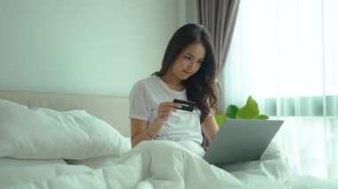 Yatakta online alışveriş yapmak için dizüstü bilgisayar kullanan Asyalı kadınlar. 