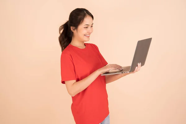 Красивая Азиатская Женщина Красной Рубашке Держит Ноутбук Кремовом Фоне — стоковое фото