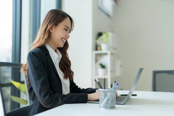 Shot of happy young asian woman, Attractive businesswoman working on laptop in her workstation office.