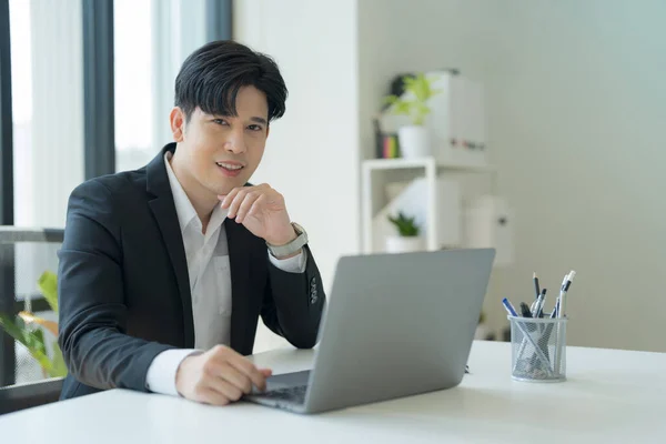 Shot of happy young asian businessman, Attractive businessman working on laptop in workstation office.