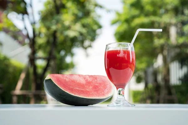 Watermelon juice and watermelon slices on the natural background in the garden.