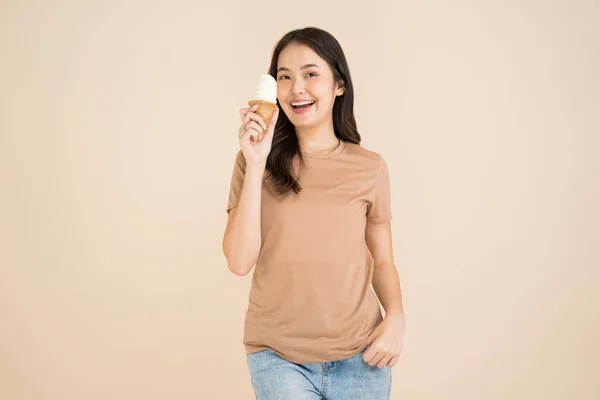 快乐的年轻女子站在褐色的背景上吃着冰淇淋 — 图库照片