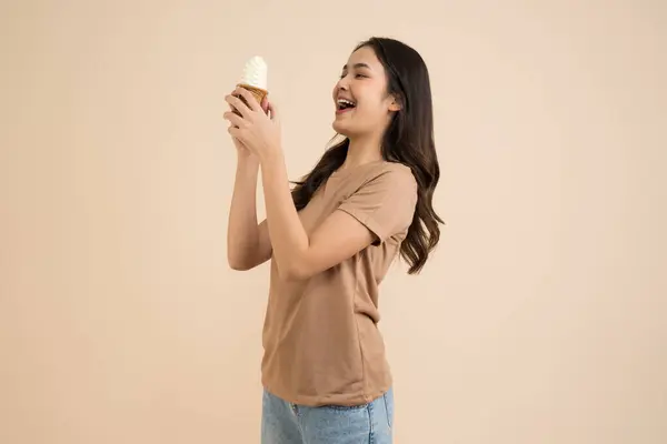 Szczęśliwa Młoda Kobieta Jedząca Lody Stojące Brązowym Tle — Zdjęcie stockowe