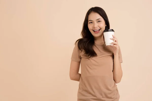 Szczęśliwa Młoda Kobieta Trzyma Filiżankę Kawy Stojąc Brązowym Tle Studio — Zdjęcie stockowe