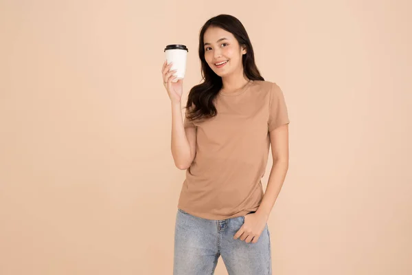 快乐的年轻女子拿着咖啡杯站在工作室棕色的背景下 — 图库照片