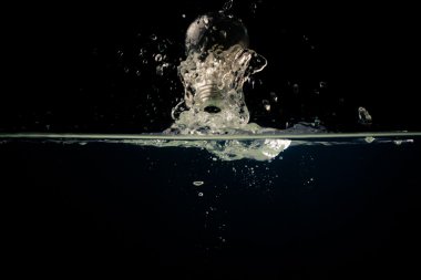 bir ampul içine düşen temiz su ile koyu arka plan