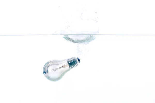 En glödlampa som faller i klart vatten med vit bakgrund Stockbild