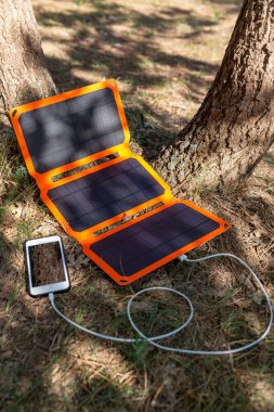 Akıllı telefon yaz kampında güneş pilinden şarj oluyor. Yürüyüşte kullanmak için temiz enerji.