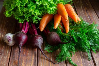 Bir demet taze havuç ve pancar üstü, sarımsak ve marul kahverengi ahşap arka planda..