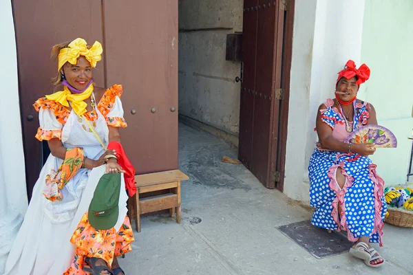 Havana, Küba, takriben Mayıs 2022: Geleneksel giyinmiş Kübalı Kadın bir evin önünde oturuyor