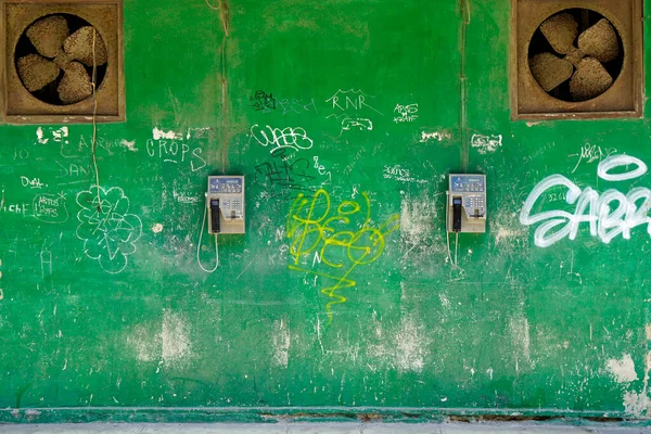 Havana, Küba, Mayıs 2022: Çürük hayranlar ve ankesörlü telefonlar greel duvarda