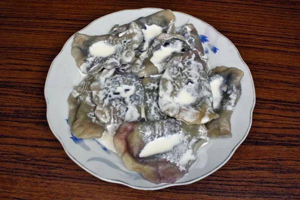 Dumplings with blueberries on a plate topped with cream — Stock Photo, Image