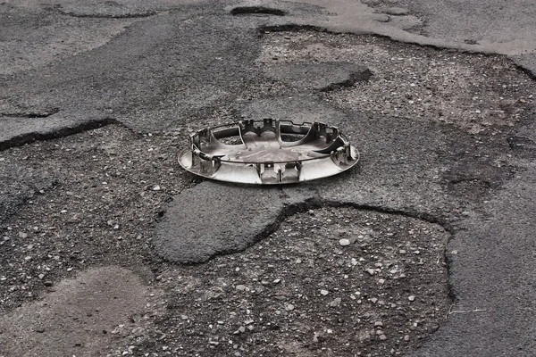 Wheel cover clipped on the damaged road — Stock Photo, Image