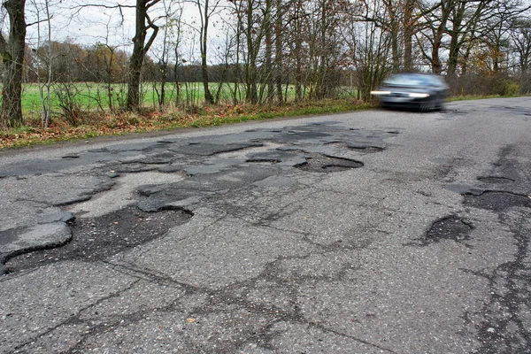 Car and holes in the asphalt — Stock Photo, Image