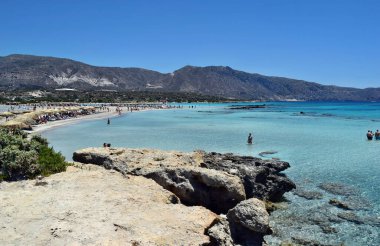 Elafonisi plajı, Girit - 18 Haziran 2021: Muhteşem turkuaz suyu ve kırmızı / pembe kumla tropikal plajı görmek