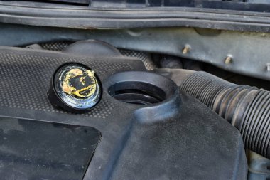 Yağ kapağının altındaki kalın, yağlı sarı motor yağı şişmiş bir contanın belirtisi ve belirtisidir. Bir araba bozuldu.