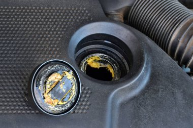 Yağ kapağının altındaki kalın, yağlı sarı motor yağı şişmiş bir contanın belirtisi ve belirtisidir. Bir araba bozuldu.