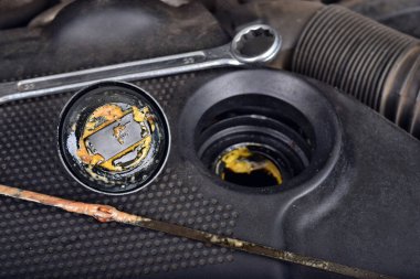 Yağ kapağının altındaki kalın, yağlı sarı motor yağı şişmiş bir contanın belirtisi ve belirtisidir. Bir araba bozuldu.