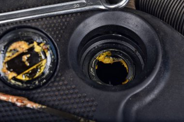 Yağ kapağının altındaki kalın, yağlı sarı motor yağı şişmiş bir contanın belirtisi ve belirtisidir. Bir araba bozuldu.