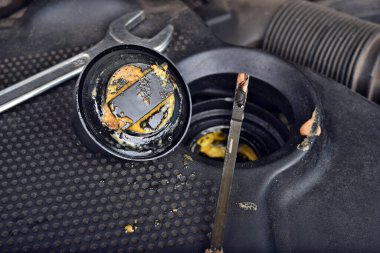 Yağ kapağının altındaki kalın, yağlı sarı motor yağı şişmiş bir contanın belirtisi ve belirtisidir. Bir araba bozuldu.