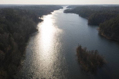 Yaz günü güneş ve ormanın yansımalarıyla uzun göl manzarası..