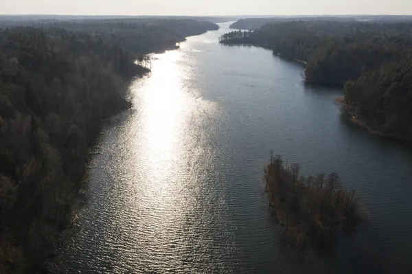 Yaz günü güneş ve ormanın yansımalarıyla uzun göl manzarası..