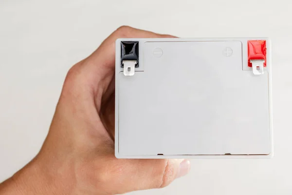Person holding white rechargeable battery for uninterruptible power supply. Ready for replacement. Closeup view.
