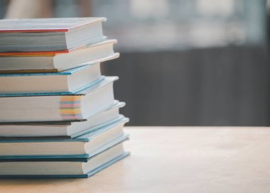 Pek çok kitabın basit bir kompozisyonu, ahşap masa üzerindeki kitap yığını veya yığını, bir tanesi kopya alanı ile açılır.