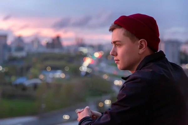 A young man thoughtfully observes the life of the city from the height — Stock Photo, Image