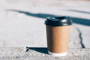 Kumlu sahilde bir fincan kağıt kahve. Denizin arka planında kahve olan çevre dostu kağıt bardak. Kapat.