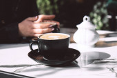 Žena v kavárně. Černý keramický šálek kávy na mramorovém stole na otevřené terase